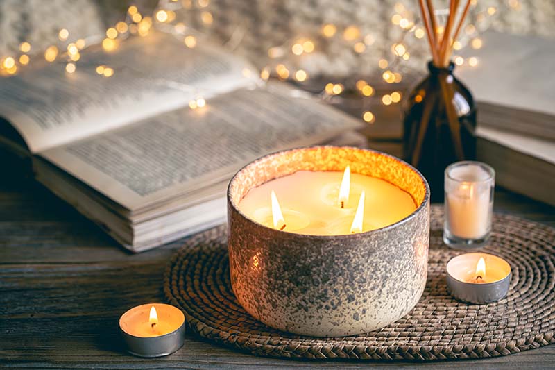 Cozy winter composition with candles on a blurred background with books.